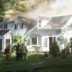Firefighters work to put out the fire on one side of the Stratton house. STEVE EDWARDS/Boothbay Register