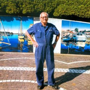 Alfred Barter stands in front of the two paintings of Boothbay Harbor scenes in Yokosuka, Japan. Courtesy photo