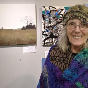 BRAF gallery manager June Rose stands next to “Pine Hill” by Nathan Campbell. JANE CARPENTER/Boothbay Register