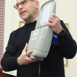 During the Dec. 11 Boothbay selectmen’s meeting, Affinity Lighting founder and president Steve Lieber holds up an LED street light he said could reduce Boothbay’s electric costs and reduce carbon emissions. BILL PEARSON/Boothbay Register