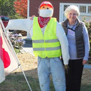 Holly Fulmer poses beside her road worker scarecrow outside her East Boothbay home as part of a neighborhood celebration of fall. BILL PEARSON/Boothbay Register