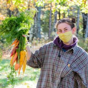 Maeve Weeder holds a bunch of carrots at the Newcastle farm last summer. Kelsey Kobik photo