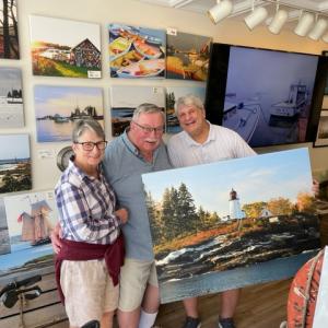 Phyllis and Gerry Allen with artist/photographer Ed Brown with a new addition to their art collection, a painting of Burnt Island. Courtesy of Susan Brown