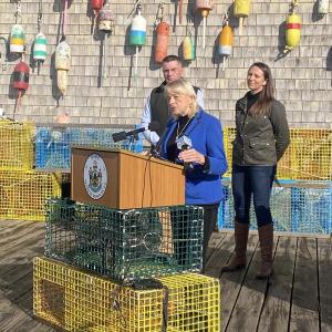 Governor Mills speaks during a press conference at Luke’s Lobster in Portland. DMR Commissioner Pat Keliher and Executive Director of the Maine Lobster Dealers Association Annie Tselikis stand behind her.