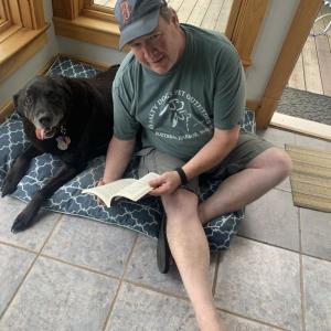 Don Kingsbury reads to his black Lab Teddy from the new book “written” by Maximus Gary called “Day of the Dogs.” BILL PEARSON/Boothbay Register
