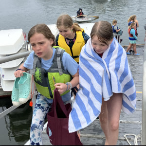 A dedicated Swim Test Buddy carries her buddy’s shoes and is
focused on getting up the ramp to serve the hot chocolate. Courtesy of Anne Grimes Rand