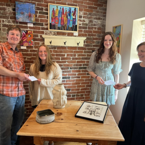 Damariscotta River Grill Owners, Tim Beal and Tamara Dica present scholarships to Maddy Scott and Ella Appell, standing in front of their artwork. Missing from the photo is Claire Colburn, whose pottery is on the front of the table. Kim Traina photo