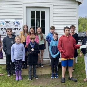 Southport students in grades 3-6, as well as their teacher Mrs. Browne and teaching principal Ms. Lisa Clarke, are shown making the presentation to Tracey Hyson, deputy treasurer of the town of Boothbay. Although the town does not oversee the Community Fridge, it is located beside the Boothbay Town Office where anyone in need may access it at any time. Courtesy photo