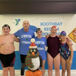 Pictured from left are Byran Hills (12), Officer Larry Brown (70), the Penquin Plunge mascot, Hannah Hills (16), Suzie Edwards (17), and Nathalie Wilson (10) before their annual friendly competitive mini-meet. Courtesy of BRYMCA