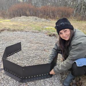 Program Manager Misha Barker sets up a firepit for BRES's new outdoor classroom. Courtesy of Erin Quinley