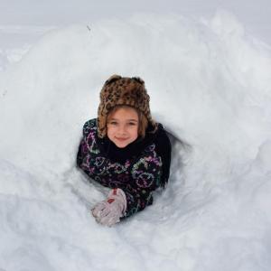 A Coastal Rivers camper shows off her quinzee, a type of snow shelter. Courtesy of Coastal Rivers