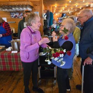 Dee and Howard Wright present roses to Community Lunch volunteer Nancy Van Dyke. Darrell Gudroe photo