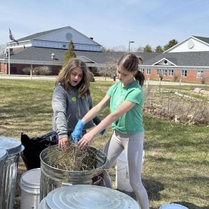 Sixth grade helpers Briar, daughter of Arianna and Brice Johnson, and Lilianna, daughter of Trista and Brian Cassidy, sprinkle hay between layers of compost in one of eight 31-gallon bins, donated by Ames True Value of Wiscasset and an EES teacher.  Students are residents of Alna and Edgecomb. Courtesy photo