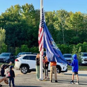 A father points out to his Pre-Ker how valuable the “big kids” are in the everyday functioning of Edgecomb Eddy School.  Raising the flag are Maxine, daughter of Pascale and Kirk Zehm;  Bryson, son of Melissa and Joseph Hersom;  Mason, son of Nicole McKay and Patrick Wenners;  and Sam, son of Daniel and Maureen Cooper.  Students are residents of Alna and Edgecomb. Courtesy photo