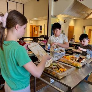 Fourth grader Joshua, son of Alma Stetson, and second grader Knowlyn, son of Nicole and Jason Blake, contribute their leftovers to the compost bins that sixth grade helper Lilianna, daughter of Trista and Brian Cassidy, will take out to the garden bins. Courtesy photo