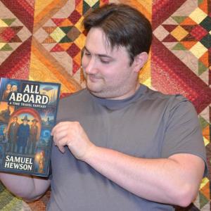 Author Samuel Hewson with an artificial intelligence mock-up of the cover for his book first "All Aboard" a time travel adventure.  Eleanor Busby photo