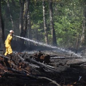A firefighter sprays hotspots in Waldoboro, Aug. 9, 2025, during a brush fire. Two days later, Aug. 11, St. George firefighters extinguished an approximate 30' x 30' brush fire on inner edge of a quarry off River Road. (Photo by Sarah Thompson)