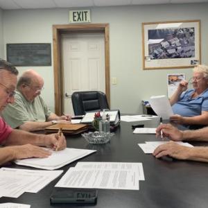 Boothbay Harbor Sewer District trustees overlook their draft agreement with Coastal Maine Bontantical Gardens. Pictured, from left: Russell Hoffman, Jim Stormont, Chris Higgins and Deryl Kipp. 