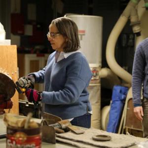 A workshop participant sharpens the edges of a spade with a grinding tool. Courtesy photo