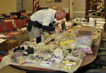 Officer Mercier searches through some of the goods recovered from the Fuller residence at Boothbay Harbor Town Office March 28. Police have thousands of items to sort through and compare to individual itemized lists from area burglaries. SUE MELLO/Boothbay Register