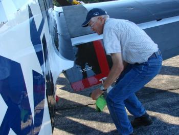 Dave Murphy, father of Texas Flying Legends Museum Warbirds pilot Mark Murphy works August 5 to  clean the plane his son would fly Tuesday. The elder Murphy owns the P-51. SUSAN JOHNS/Wiscasset Newspaper