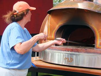 Shelly McLellan takes a wood-fired pizza out of her custom made oven. SUZI THAYER/Boothbay Register